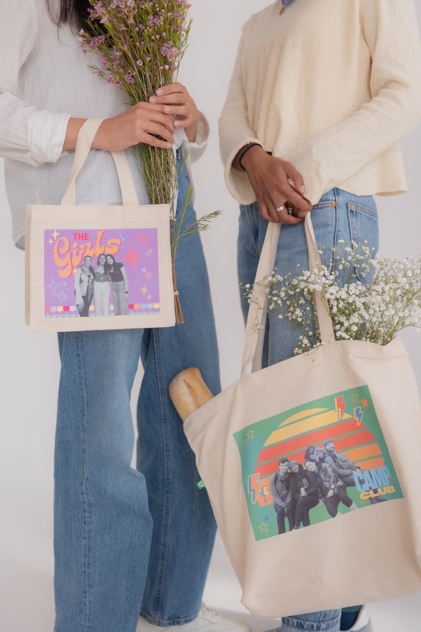Two people holding tote bags with colorful designs on a white background
